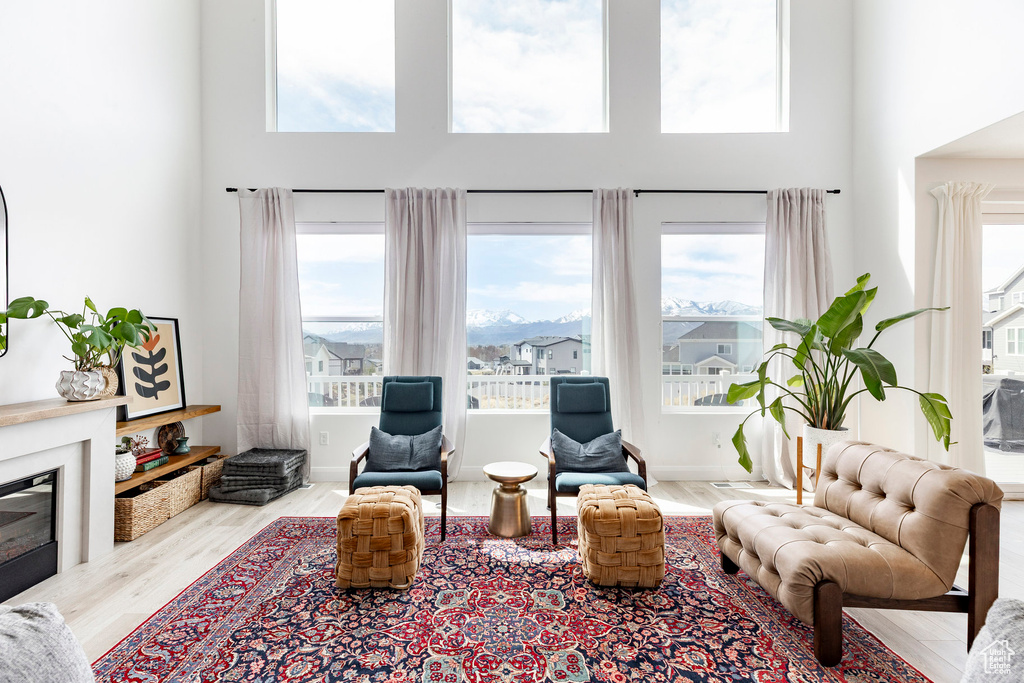 Living area with a high ceiling, a glass covered fireplace, and wood finished floors