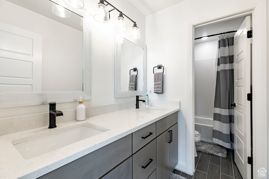 Full bathroom with a sink, toilet, double vanity, and shower / tub combo