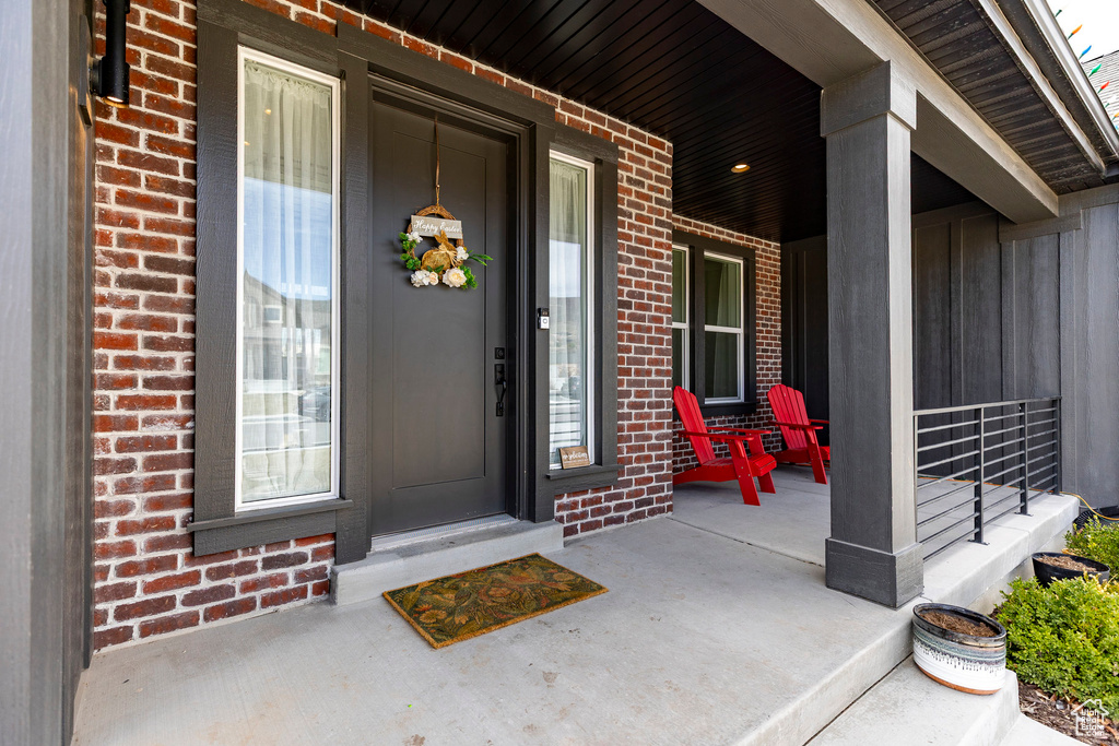 Entrance to property featuring a porch and brick siding