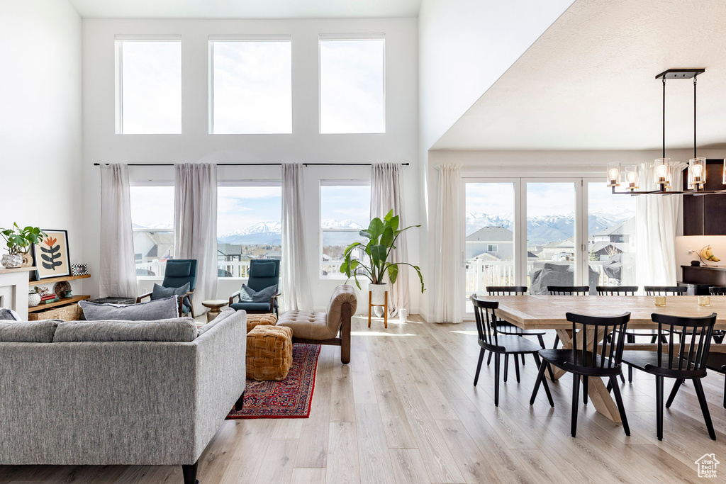 Living area featuring an inviting chandelier, a high ceiling, and light wood-type flooring