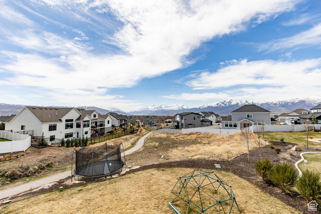 View of yard featuring a trampoline, a mountain view, a residential view, and fence