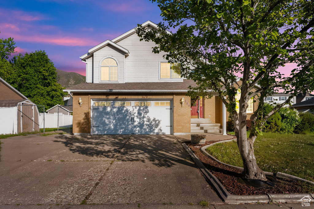 Traditional home with brick siding, a garage, fence, and driveway