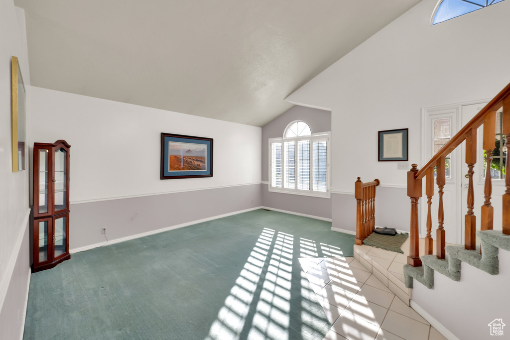 Unfurnished living room featuring carpet flooring, baseboards, stairway, and high vaulted ceiling