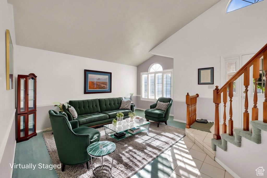 Living room with baseboards, stairs, light tile patterned floors, and high vaulted ceiling