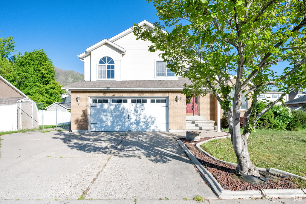 Traditional-style house with concrete driveway, brick siding, fence, and a garage
