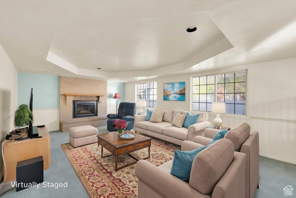 Living room featuring a tray ceiling, a wainscoted wall, carpet, and a fireplace