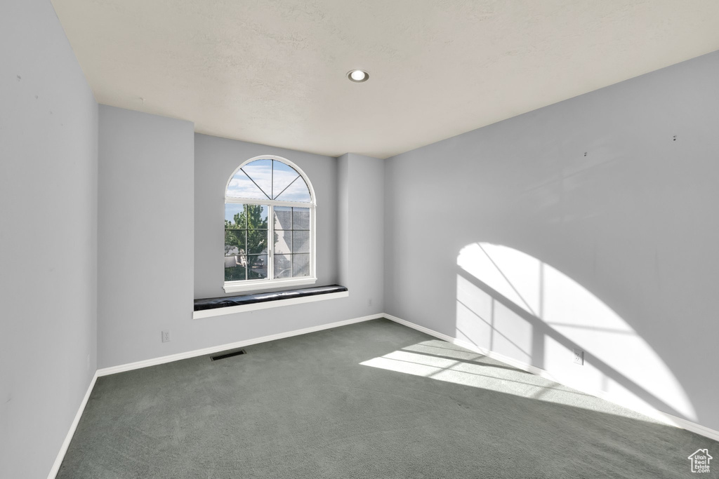 Carpeted spare room featuring baseboards and visible vents