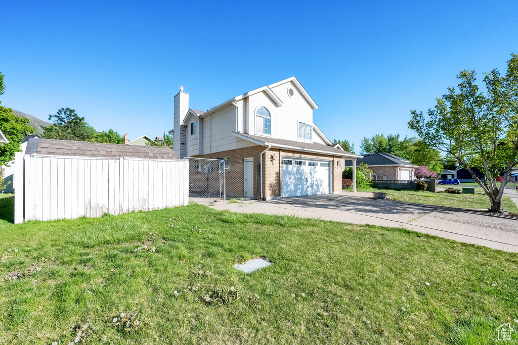 Exterior space with fence, brick siding, a garage, a front yard, and driveway