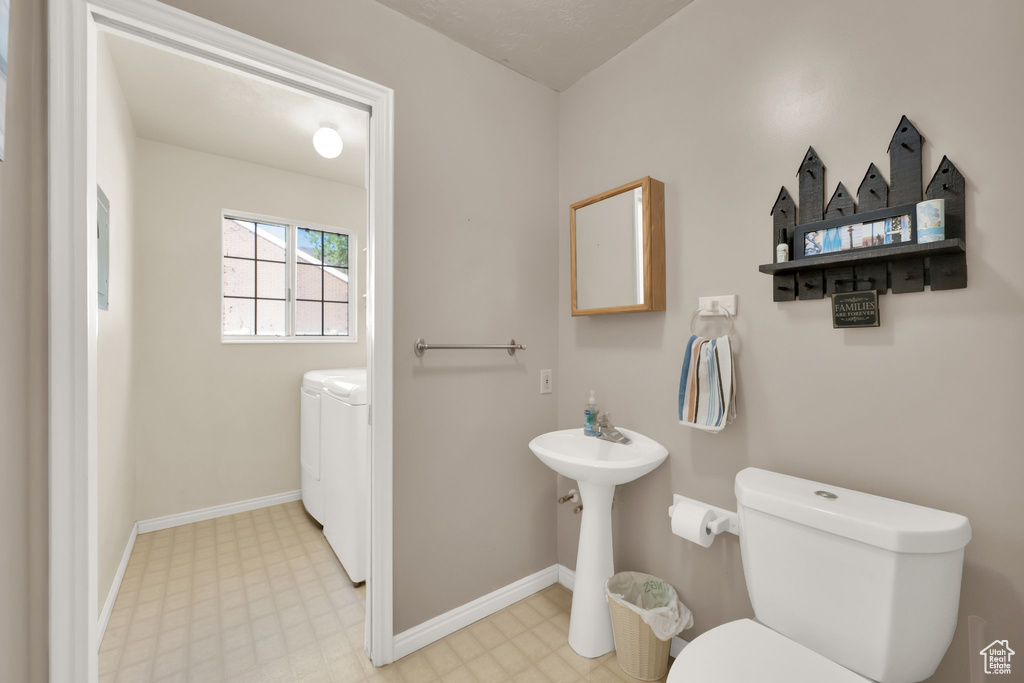 Half bathroom featuring tile patterned floors, baseboards, toilet, and washer and clothes dryer