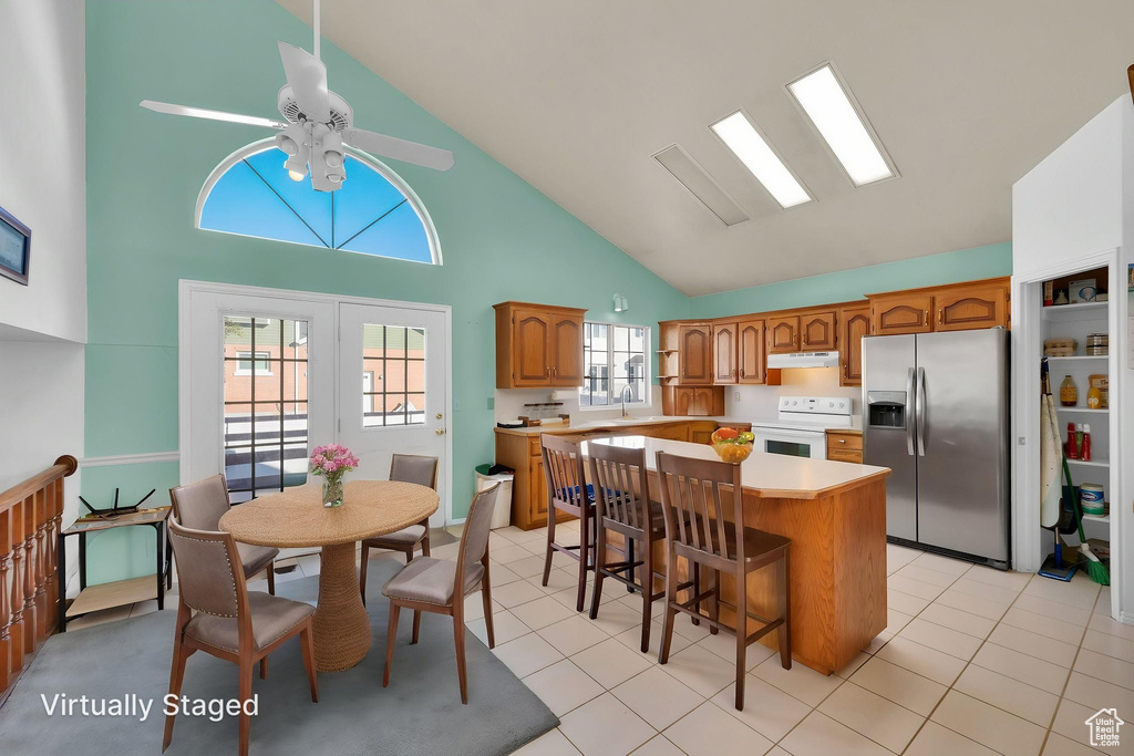 Kitchen with a kitchen island, electric range, brown cabinets, stainless steel fridge with ice dispenser, and high vaulted ceiling
