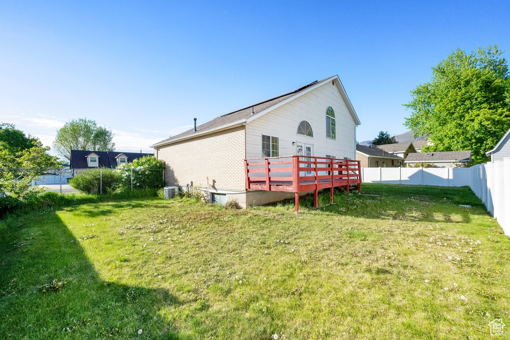 Rear view of property with a lawn, cooling unit, a wooden deck, and a fenced backyard