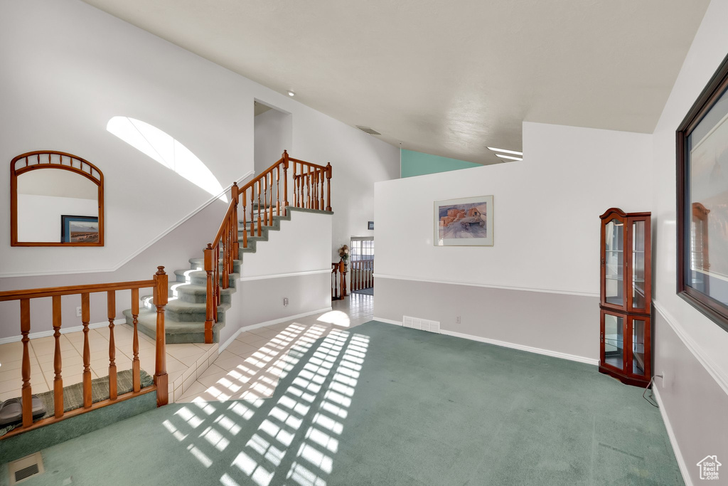 Interior space with carpet flooring, high vaulted ceiling, visible vents, and stairway