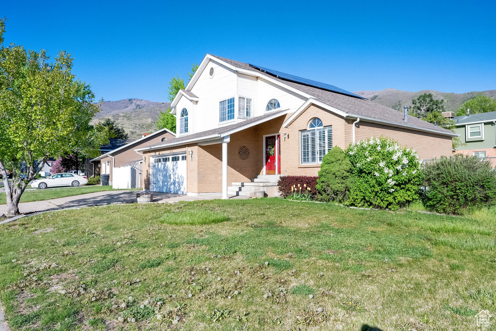 Traditional-style house featuring brick siding, a front lawn, a mountain view, and driveway