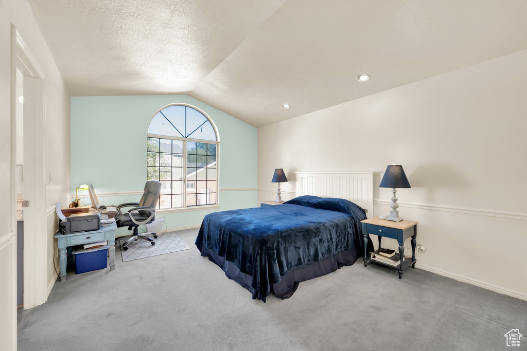Carpeted bedroom with baseboards and vaulted ceiling