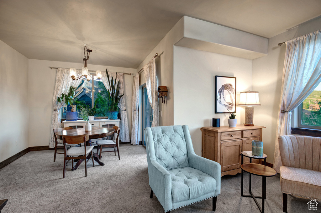 Carpeted dining space with a chandelier and baseboards
