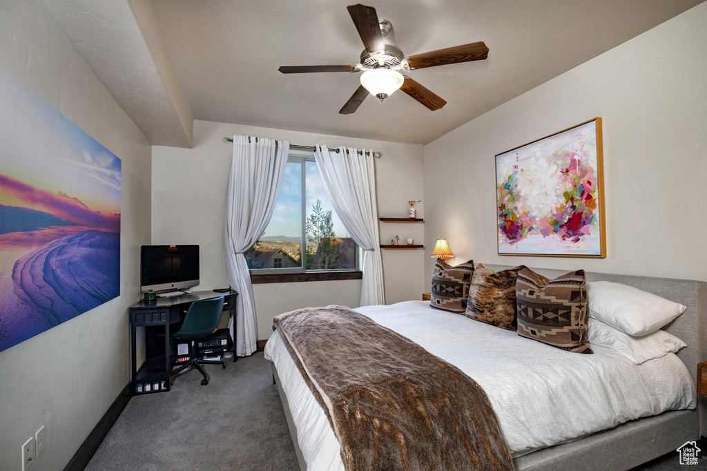 Carpeted bedroom with an office area and ceiling fan