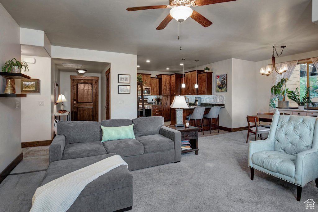 Living area with a ceiling fan, a chandelier, light carpet, and recessed lighting