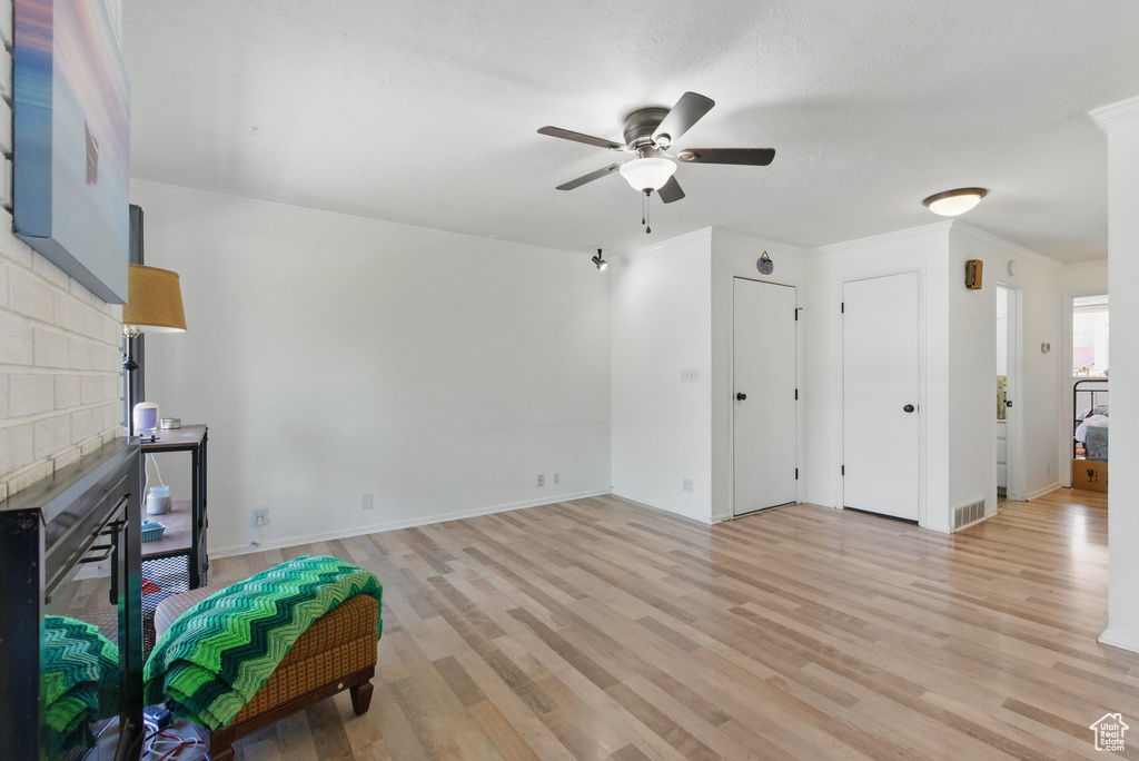Living room with ceiling fan, light wood-style floors, a brick fireplace, baseboards, and visible vents