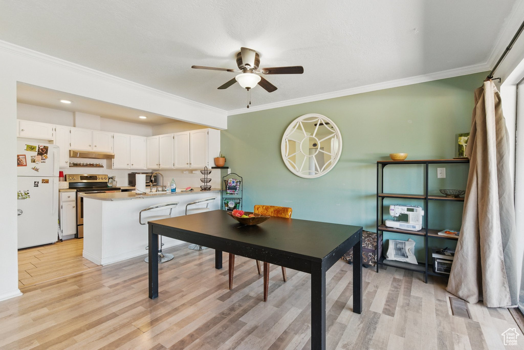 Dining area featuring crown molding, ceiling fan, light wood-style floors, and visible vents