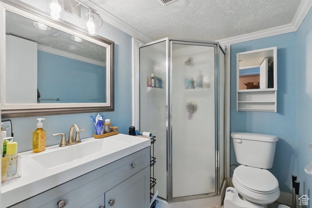 Bathroom with crown molding, a shower stall, toilet, and a textured ceiling