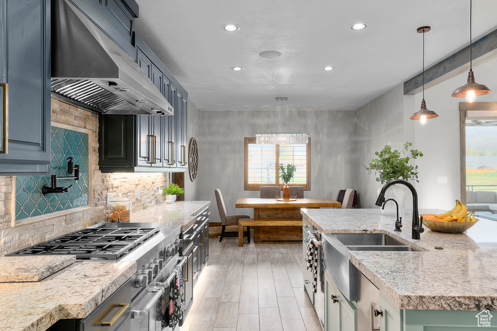 Kitchen featuring recessed lighting, backsplash, a sink, and range hood