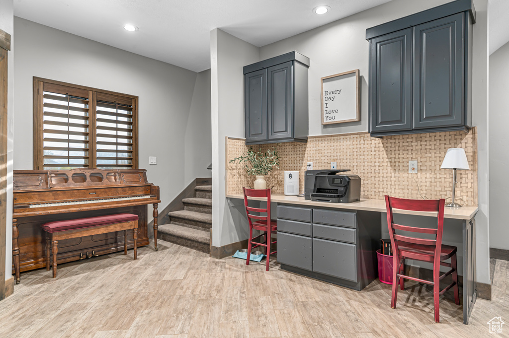 Office area with built in desk, light wood-style flooring, baseboards, and recessed lighting