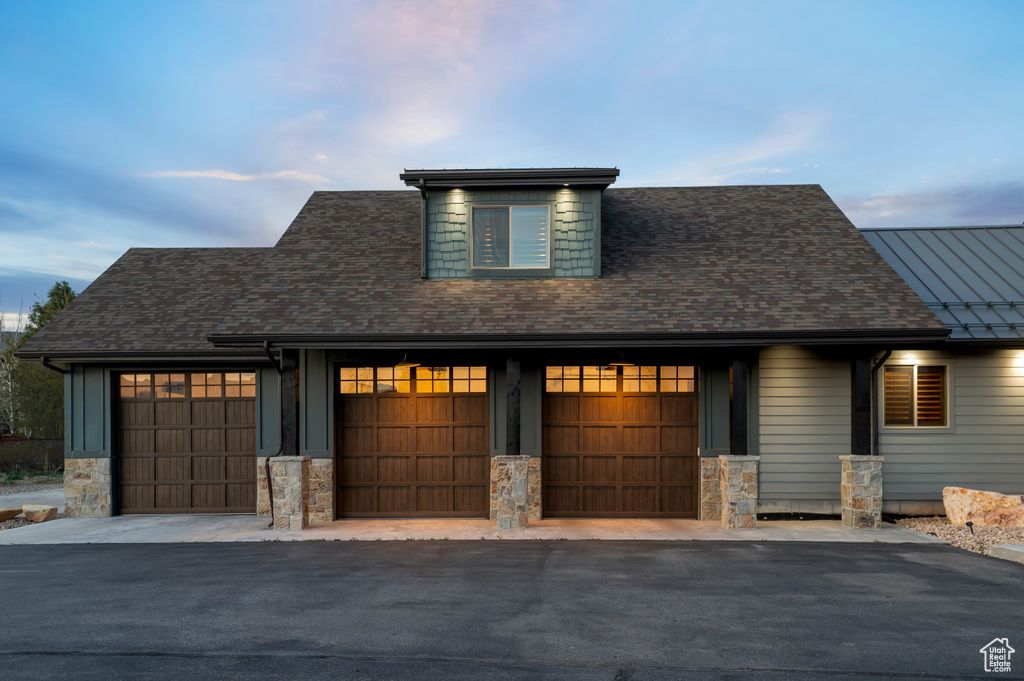 View of front of home featuring an attached garage, stone siding, and driveway
