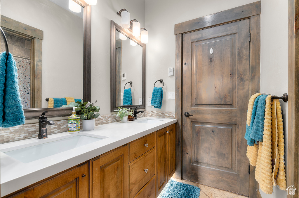 Bathroom featuring backsplash, double vanity, tile patterned floors, and a sink