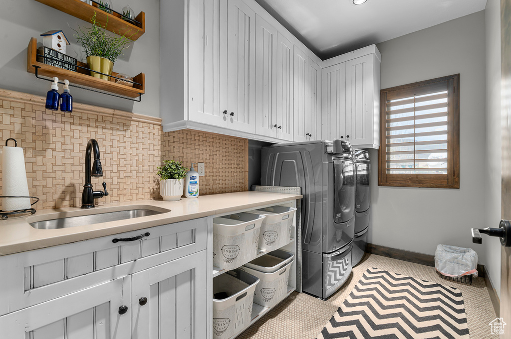 Clothes washing area featuring cabinet space, washer and dryer, and a sink