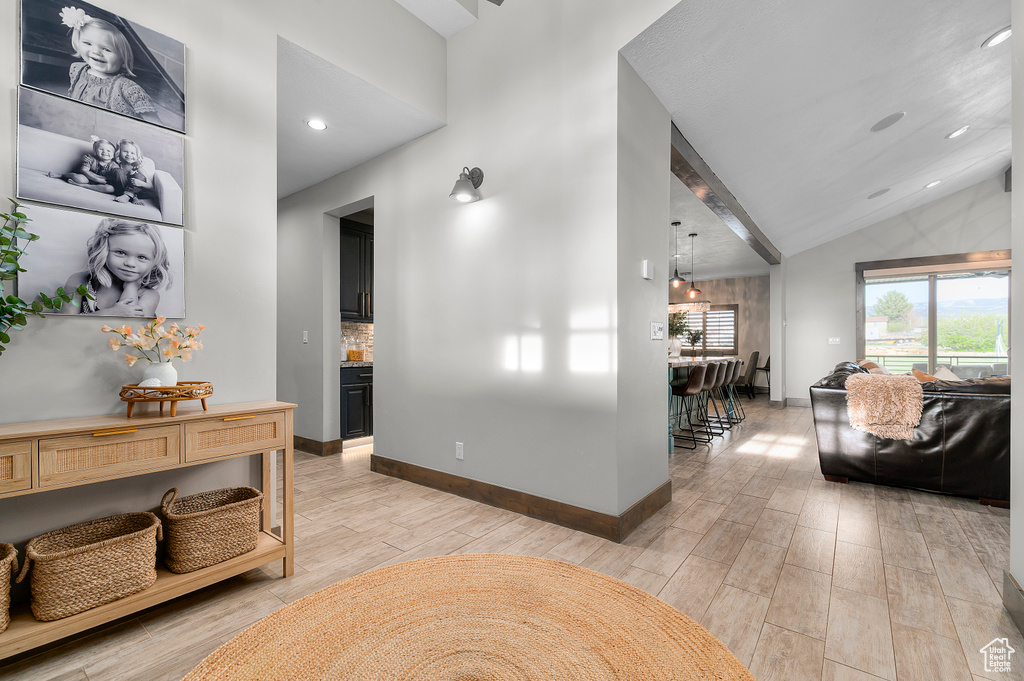 Corridor featuring lofted ceiling with beams, light wood-style flooring, baseboards, and recessed lighting