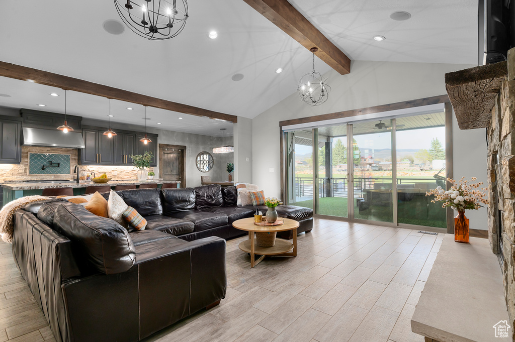 Living area featuring beamed ceiling, light wood finished floors, a notable chandelier, and high vaulted ceiling