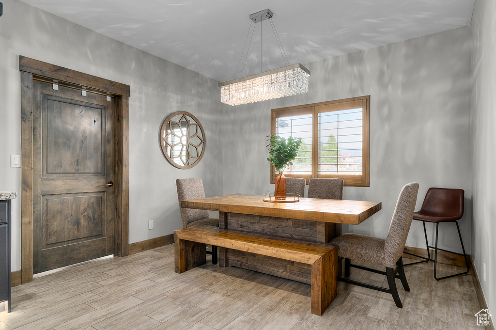 Dining area featuring light wood-style floors, baseboards, and a notable chandelier