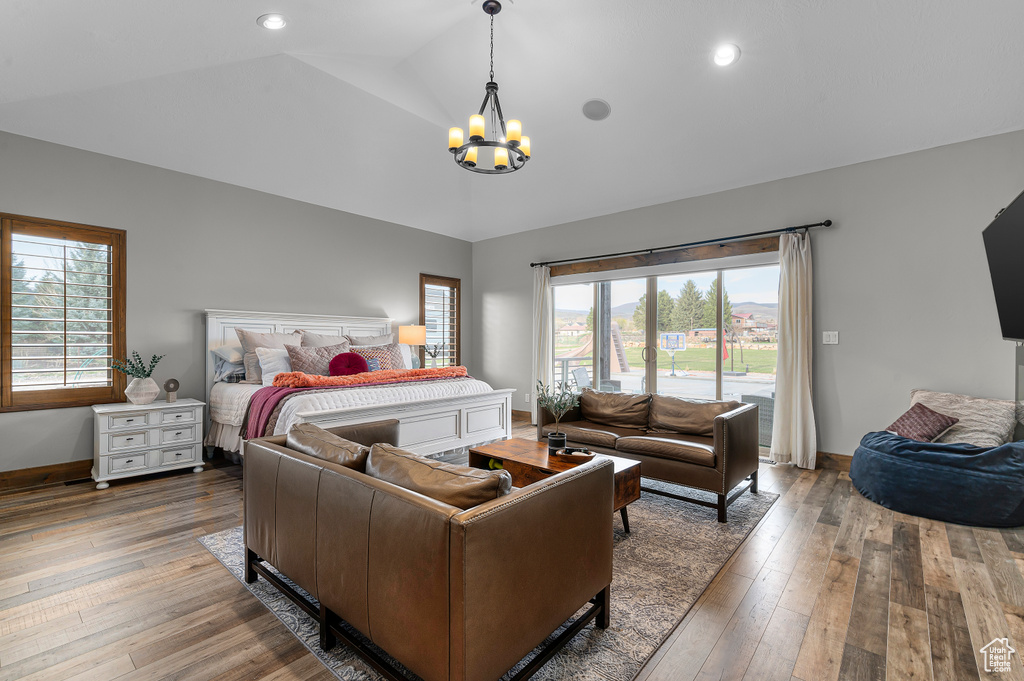 Bedroom with wood-type flooring, lofted ceiling, baseboards, and an inviting chandelier