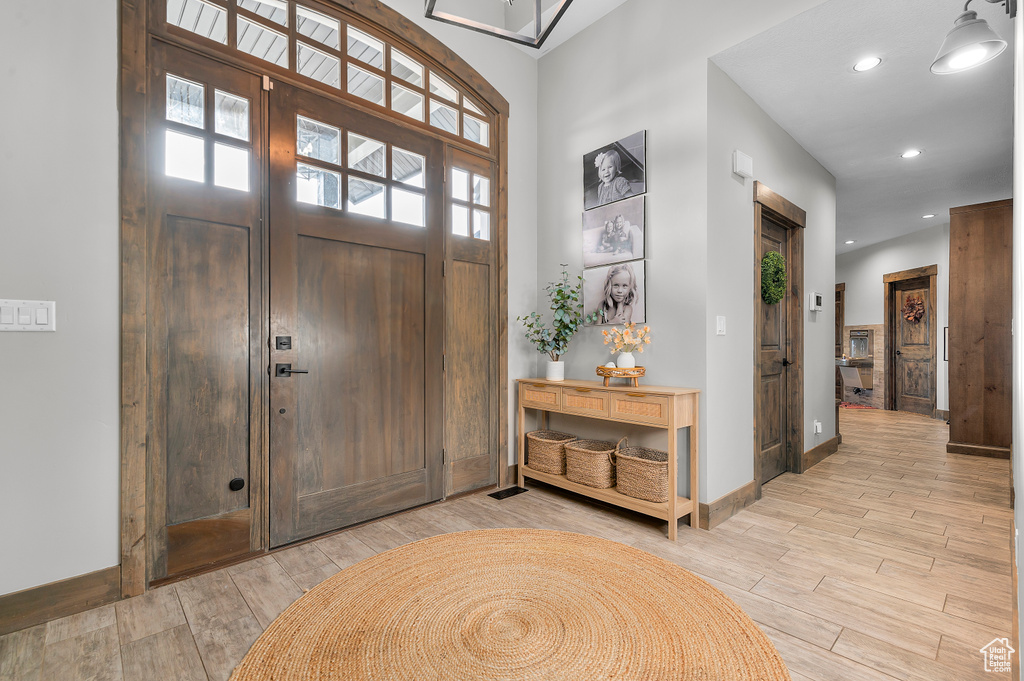 Foyer with baseboards, a healthy amount of sunlight, light wood finished floors, and recessed lighting