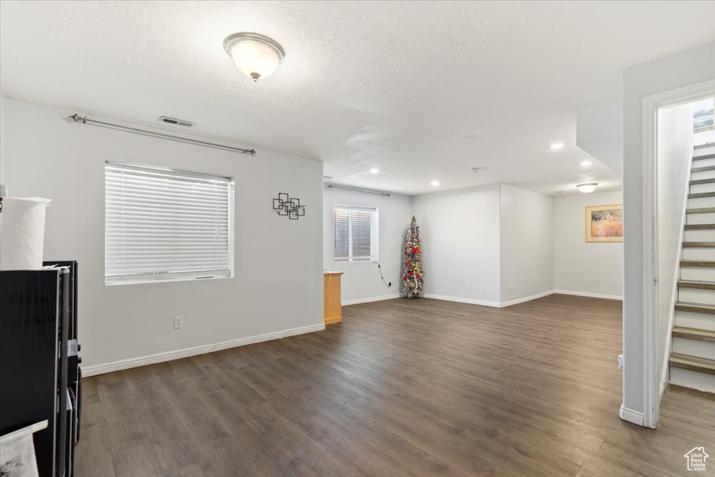 Unfurnished living room featuring visible vents, stairs, baseboards, recessed lighting, and dark wood-type flooring