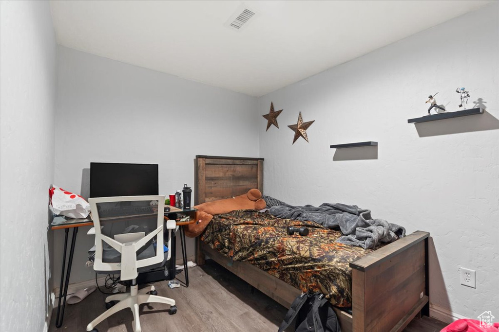 Bedroom with baseboards, visible vents, and wood finished floors