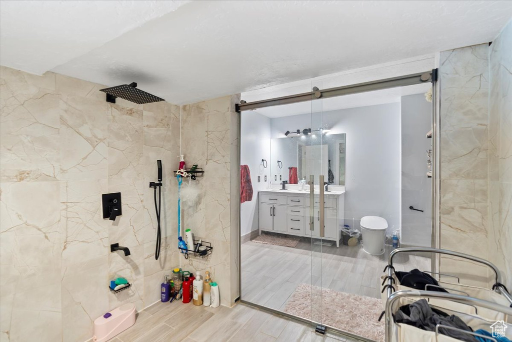 Full bath featuring vanity, wood finish floors, and a tile shower