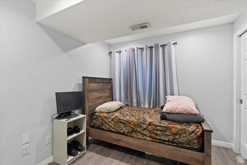 Bedroom with visible vents, baseboards, and wood finished floors