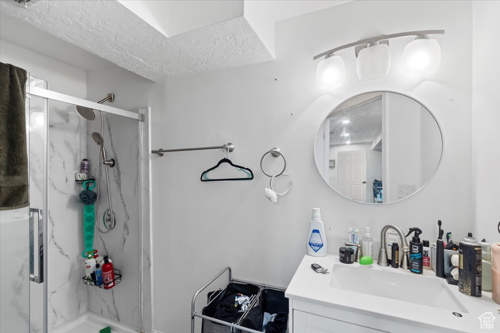 Full bath featuring a marble finish shower, vanity, and a textured ceiling