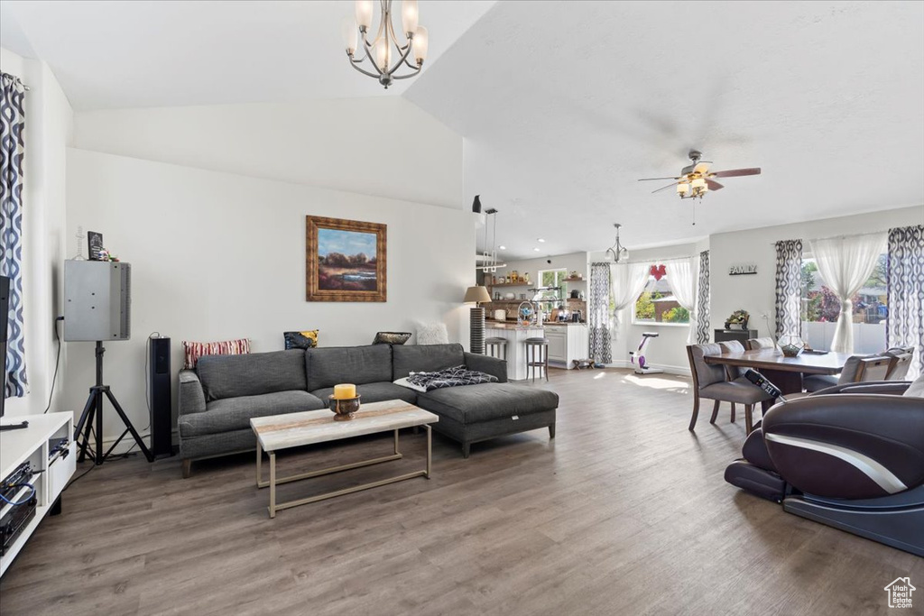 Living area featuring baseboards, ceiling fan with notable chandelier, wood finished floors, and lofted ceiling