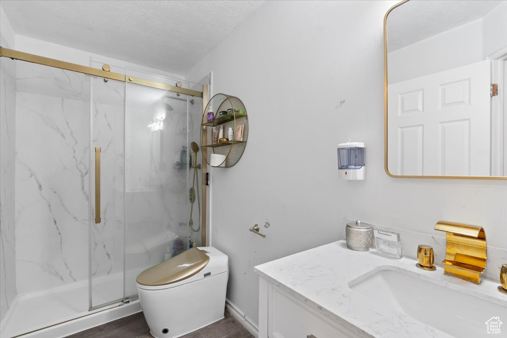 Bathroom featuring vanity, toilet, a marble finish shower, and wood finished floors