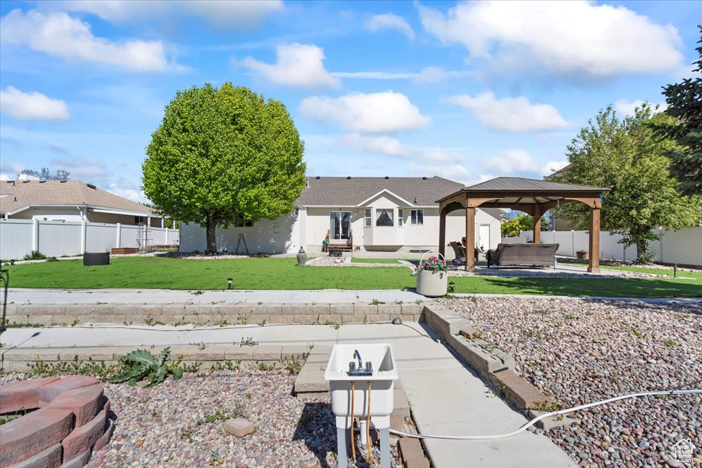 Exterior space featuring a patio area, a gazebo, fence, a yard, and stucco siding