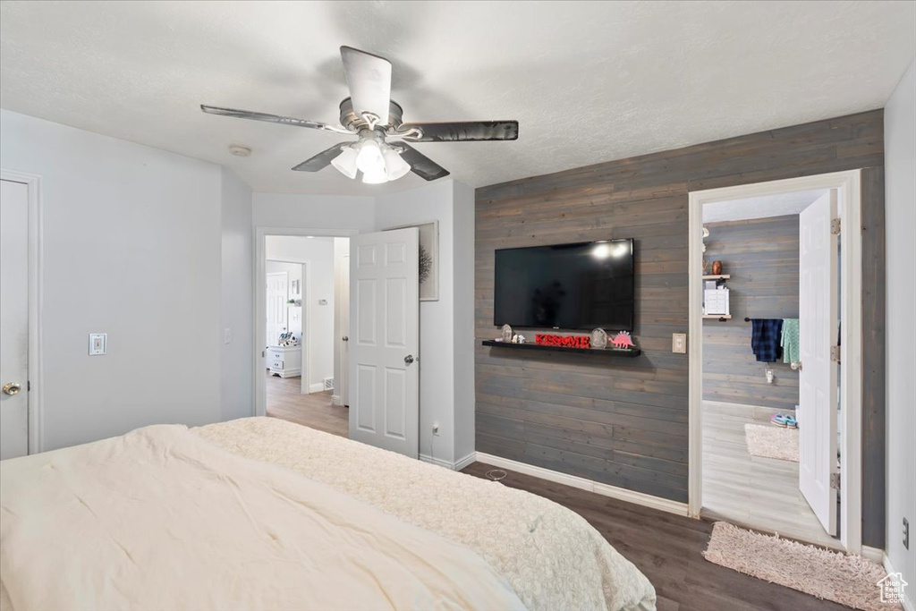 Bedroom featuring wooden walls, baseboards, wood finished floors, and an accent wall