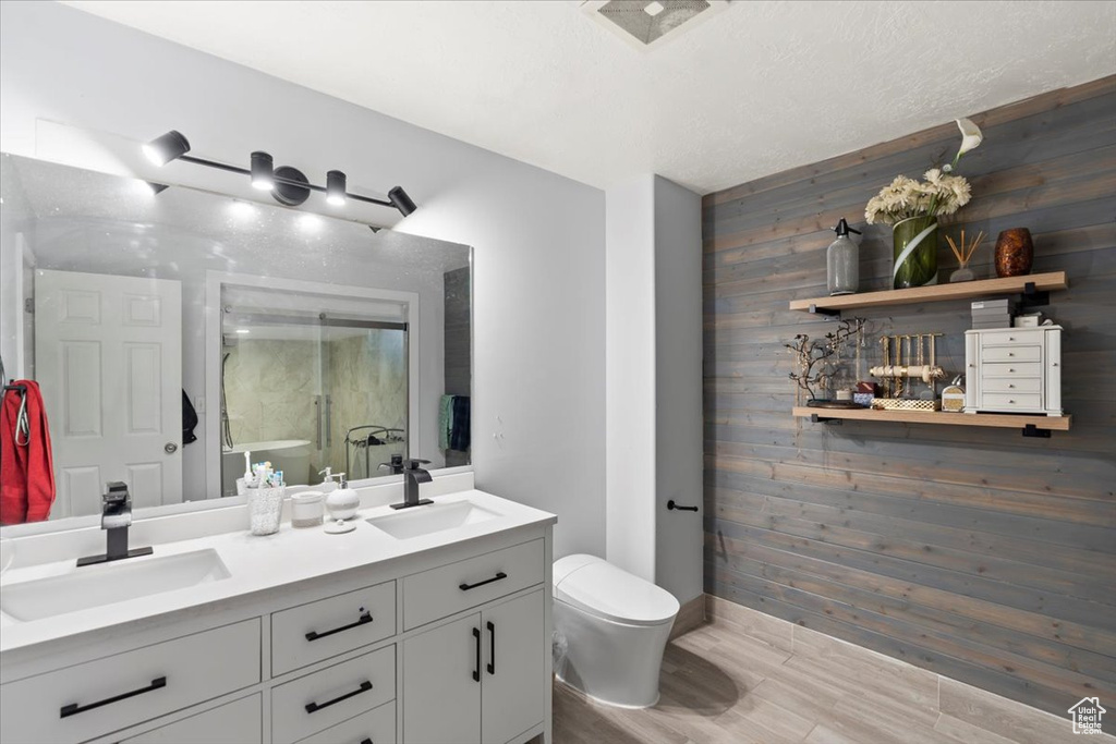 Bathroom featuring a sink, baseboards, a stall shower, and wood walls