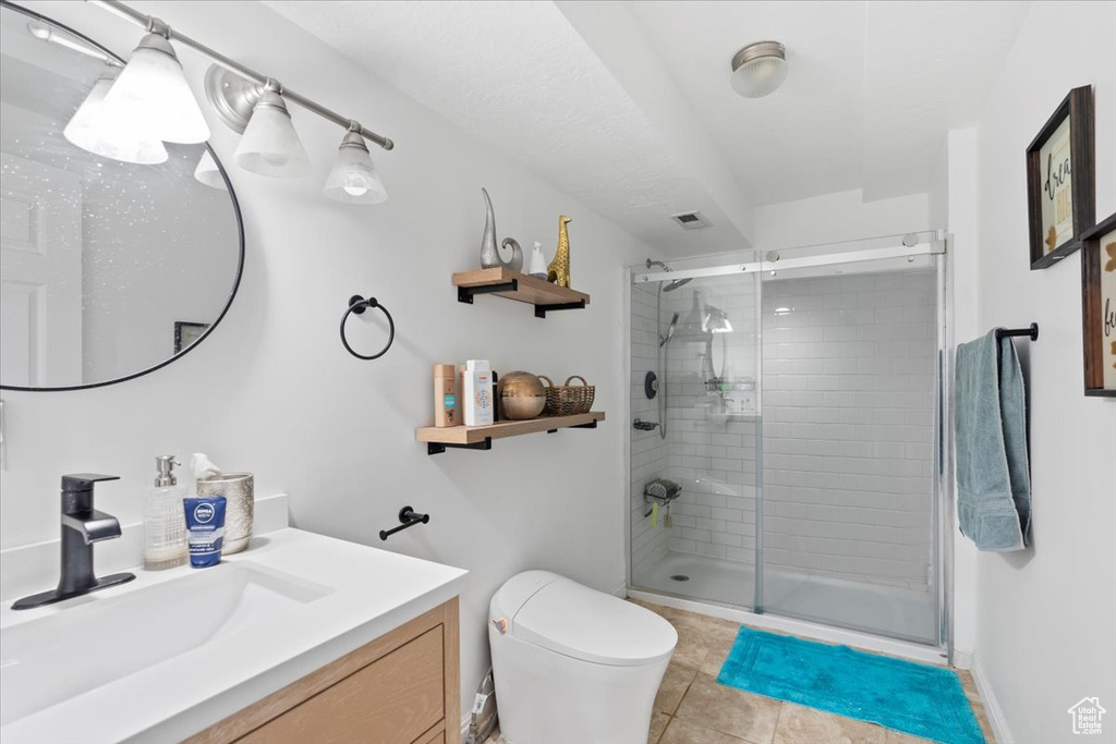 Bathroom with vanity, toilet, tile patterned flooring, and a stall shower