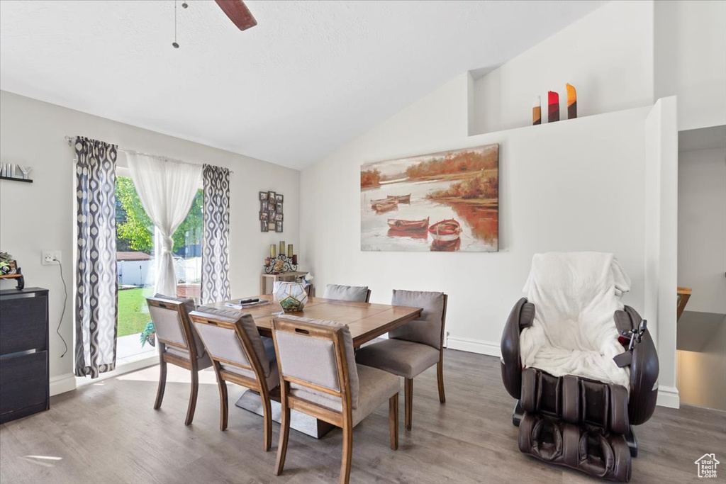 Dining space with a ceiling fan, baseboards, wood finished floors, and lofted ceiling