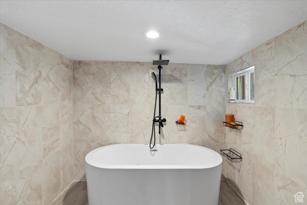 Full bath with tile walls, wood finished floors, and a freestanding bath
