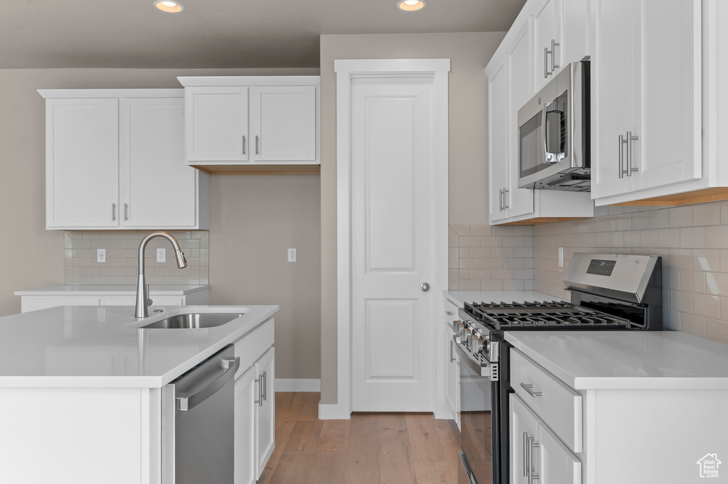 Kitchen featuring appliances with stainless steel finishes, a sink, recessed lighting, light wood-style floors, and white cabinetry