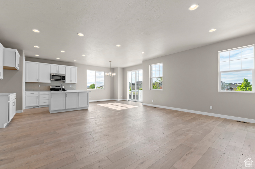 Kitchen with stainless steel appliances, open floor plan, baseboards, a chandelier, and recessed lighting