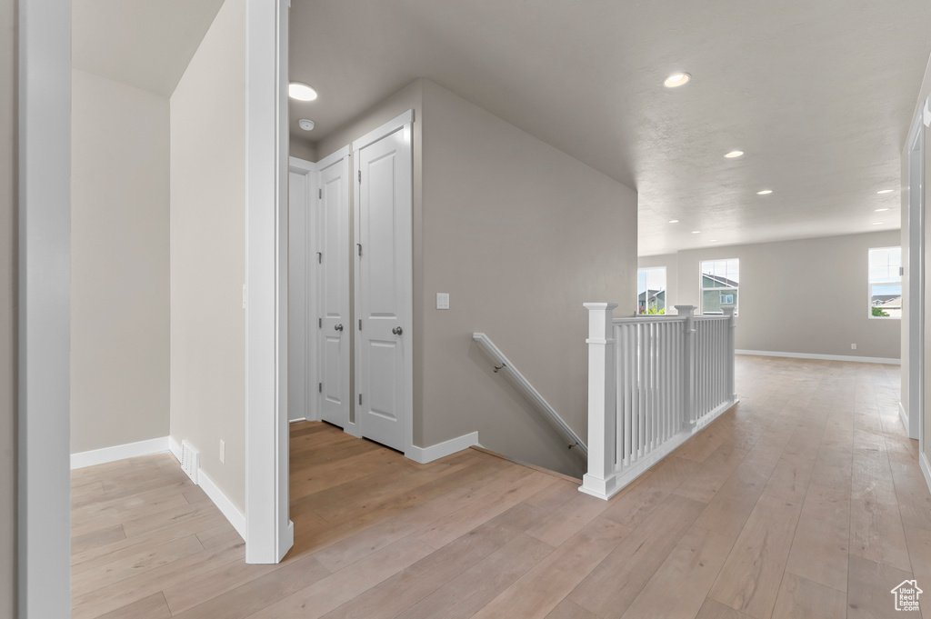 Hallway featuring an upstairs landing, light wood-style flooring, recessed lighting, and baseboards